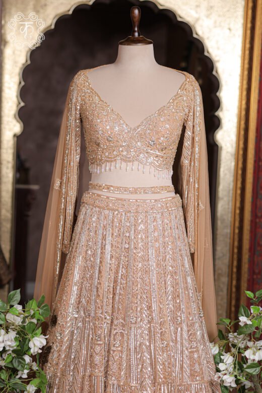 Geometrical Embroidered Sweetheart Blouse Lehenga Set featuring an embroidered sweetheart blouse, pearl tassels, attached cape sleeves, and a tiered linear skirt from Kridhaa.