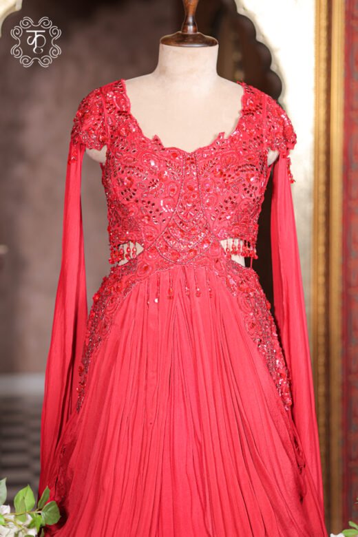 Detailed view of the floor-length sheer cape sleeve drape and pleated skirt of the Embellished Cut-Out Waist Pre-Draped Gown.