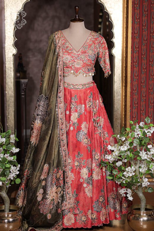 Close up of coral red V-neck blouse with zardozi embroidery, sequin work, and coin fringe hem.