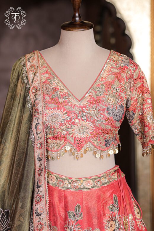 Detailed texture of coral red floral printed silk lehenga skirt with embroidered waistband and tie-up latkans.