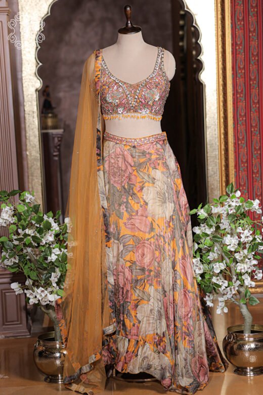 Mustard yellow floral printed silk lehenga set with hand embroidered sleeveless blouse and net dupatta.