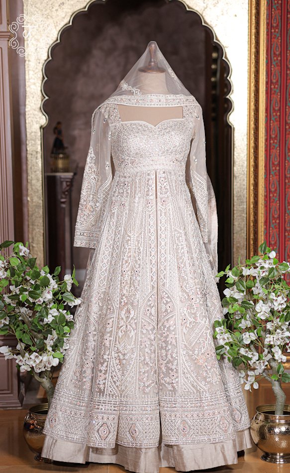 Ivory white heavily embroidered long jacket lehenga set with full sleeves on mannequin.