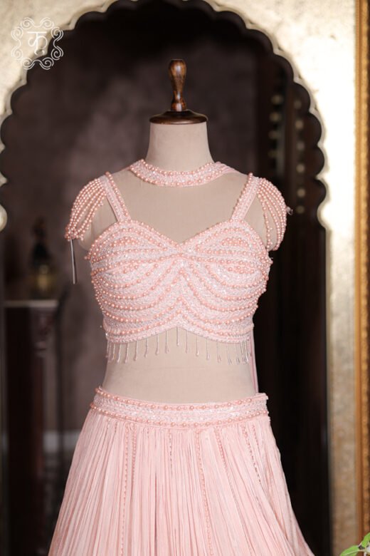 Close up of blush pink sweetheart corset top encrusted with rows of white pearls, sequins, and choker collar.