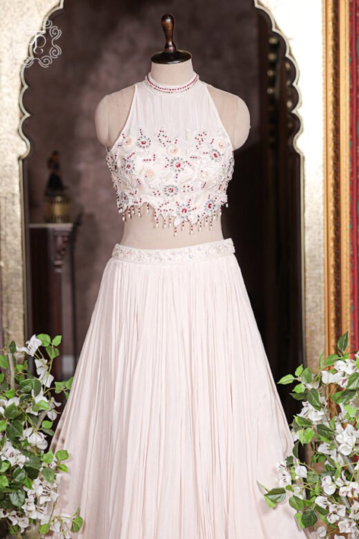 Close up of blush pink halter neck blouse with sheer yoke, pearl, crystal, and ruby red embroidery.