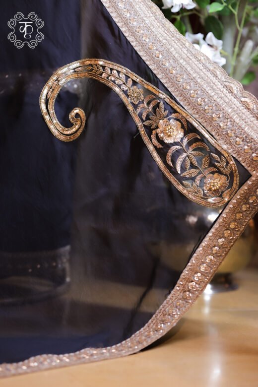 Close-up of a black sheer organza dupatta featuring a gold zardozi embroidered paisley motif and heavy sequined border