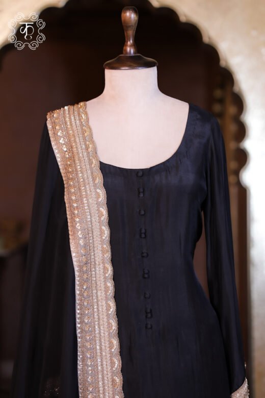 Close-up of a black silk kurta with front fabric buttons and a gold sequin-bordered dupatta on a mannequin