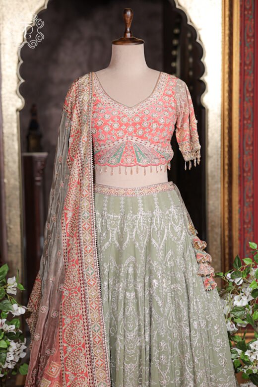 Detailed texture of sage green embroidered skirt layer parting over peach printed border and tassel latkans.