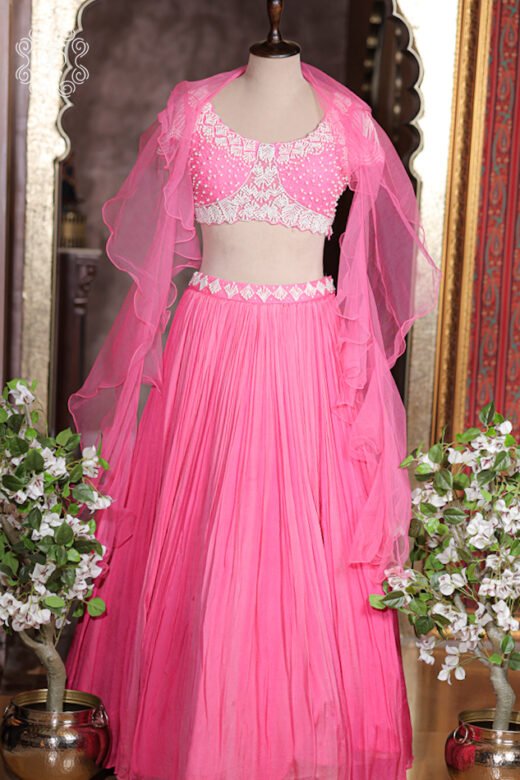 Close up of bubblegum pink sweetheart blouse with dense white pearl, beaded embroidery, and scalloped hem.