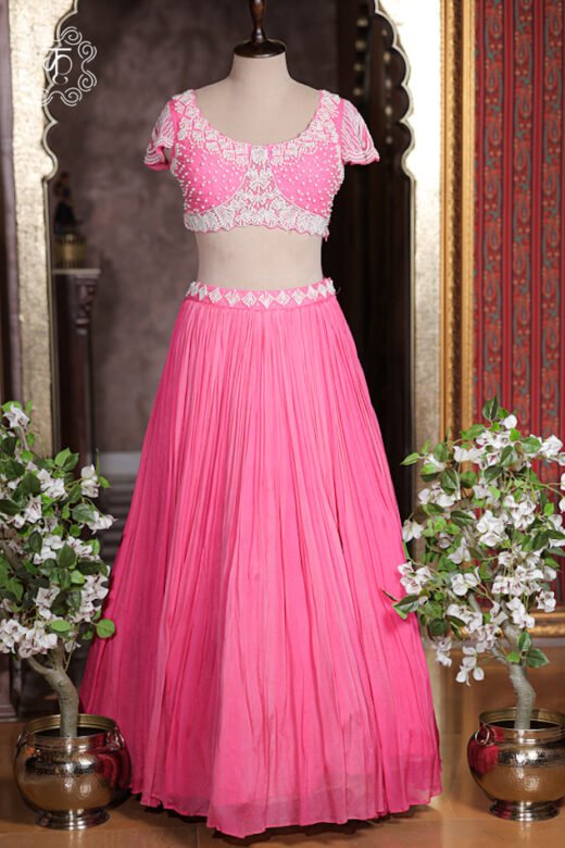 Sheer pink organza ruffled cape dupatta draped over shoulders of lehenga choli set.