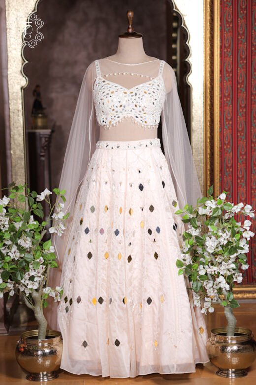 Close up of ivory white sweetheart bustier choli top encrusted with gold silver mirrors and dangling bead fringe.