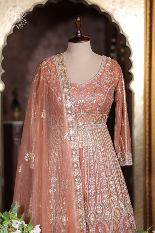 Front slit detail of embroidered jacket opening to reveal rich rust orange silk lehenga skirt underneath.