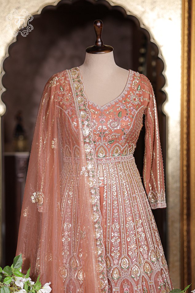 Front slit detail of embroidered jacket opening to reveal rich rust orange silk lehenga skirt underneath.