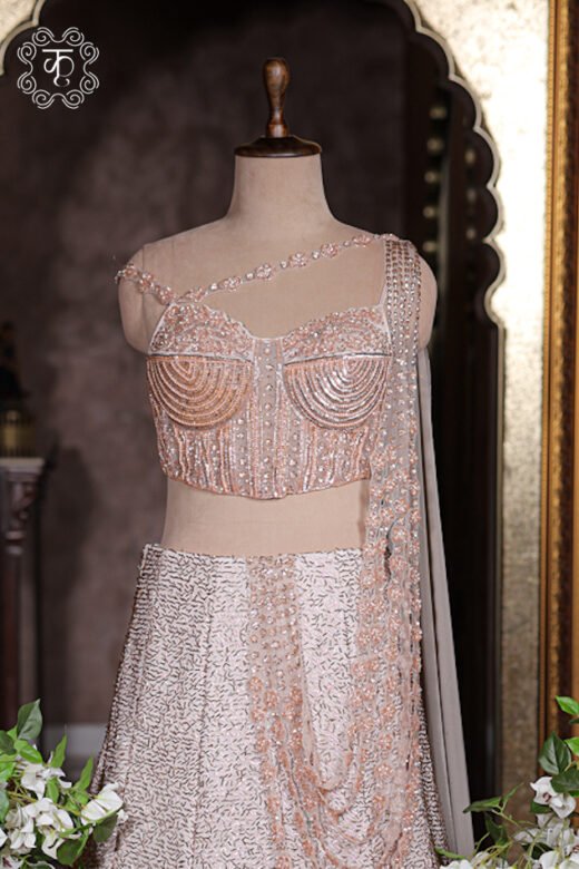 Pre-stitched draped pallu on blush pink lehenga featuring multi-layered cascading pearl string details.