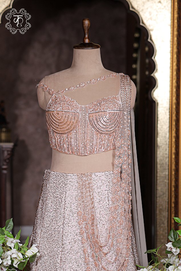 Pre-stitched draped pallu on blush pink lehenga featuring multi-layered cascading pearl string details.