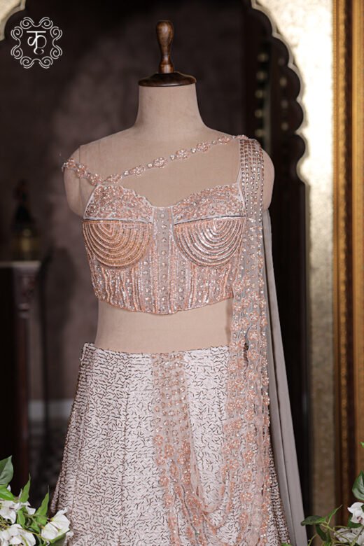 Close up of blush pink corset bustier top with structured boning, concentric sequin work, and floral strap.