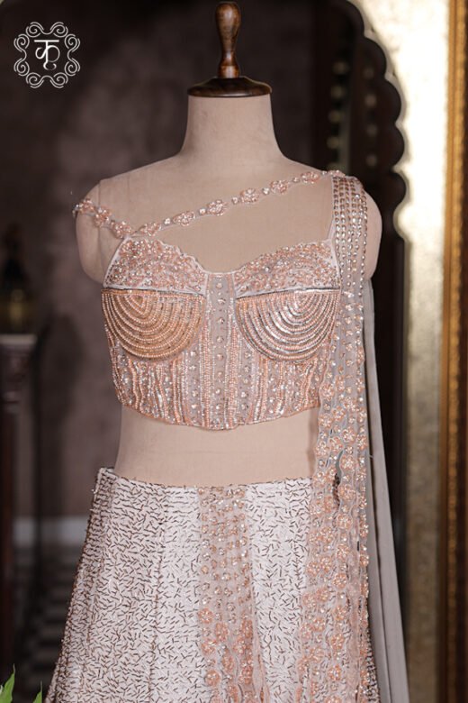 Blush pink sequined corset lehenga set with attached draped pallu and cascading pearl details.